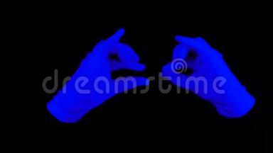 幻影表演中的紫外线手套。 在黑色灯光场景中，在黑色背景上交互蓝手。